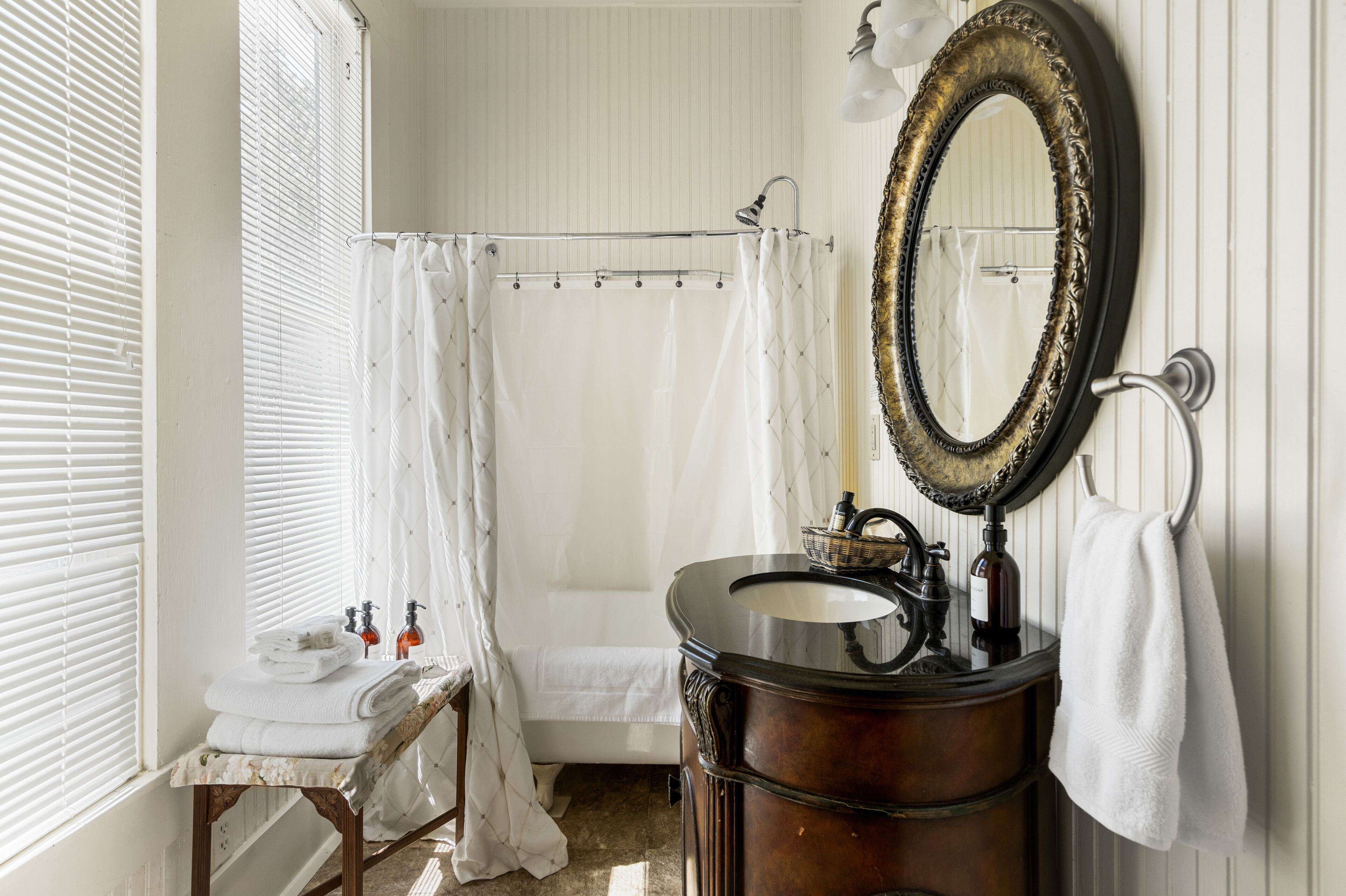 Un baño con un lavamanos antiguo, un espejo grande y una cortina de ducha.