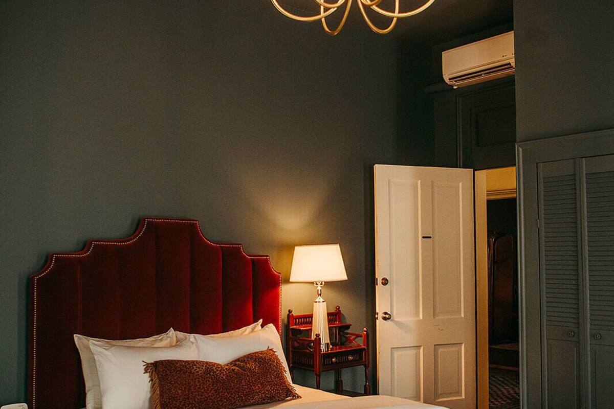 Une chambre d’hôtel avec un grand lit, un lustre, une table de chevet, une lampe, une armoire et un appareil de climatisation.
