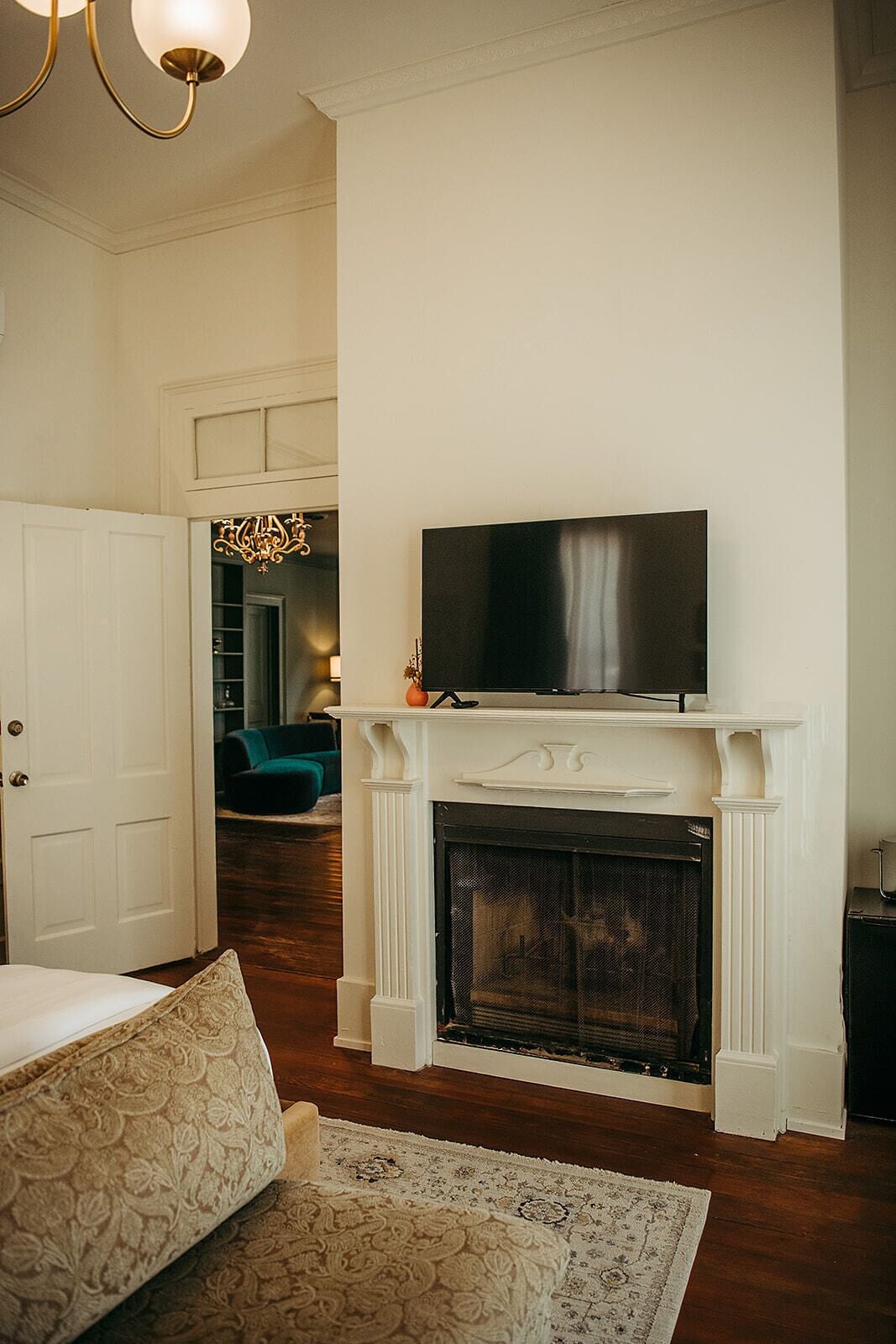 A living room with a fireplace, a television on top, a door, and a patterned rug.