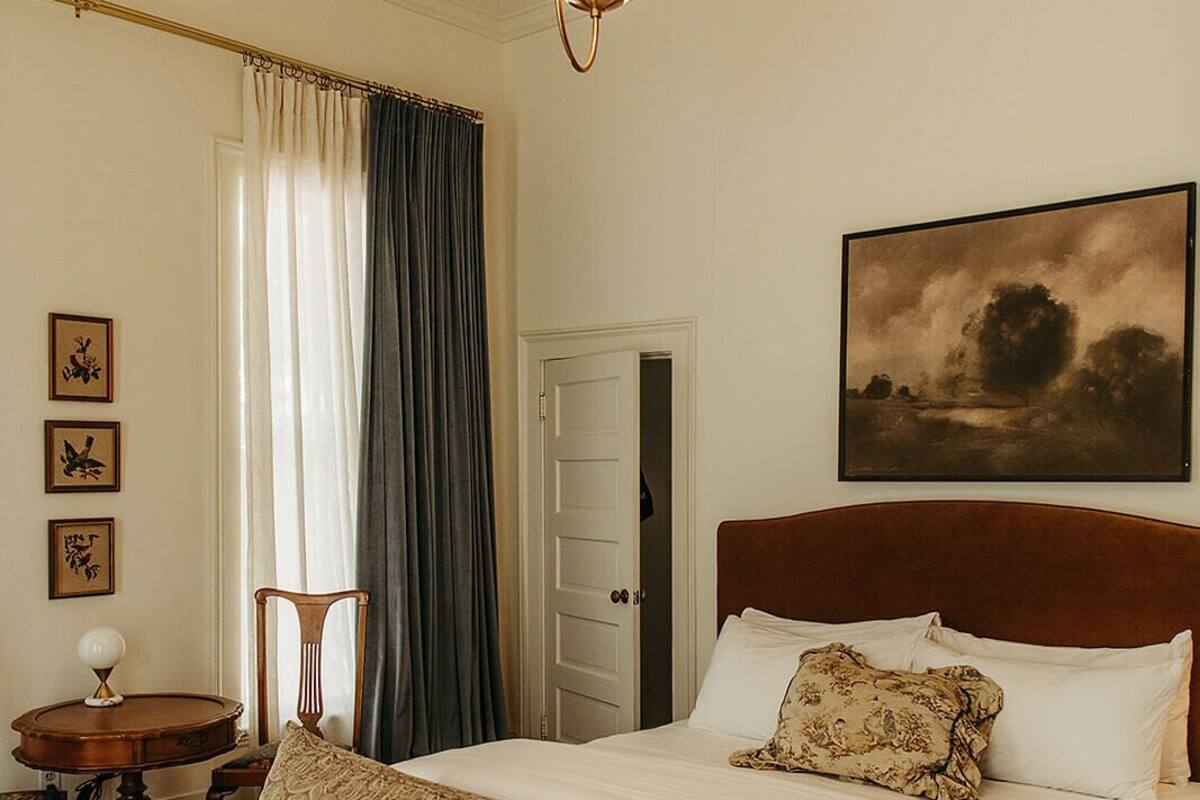 Une chambre à coucher avec un lit, une chaise, une table et un tableau accroché au mur.