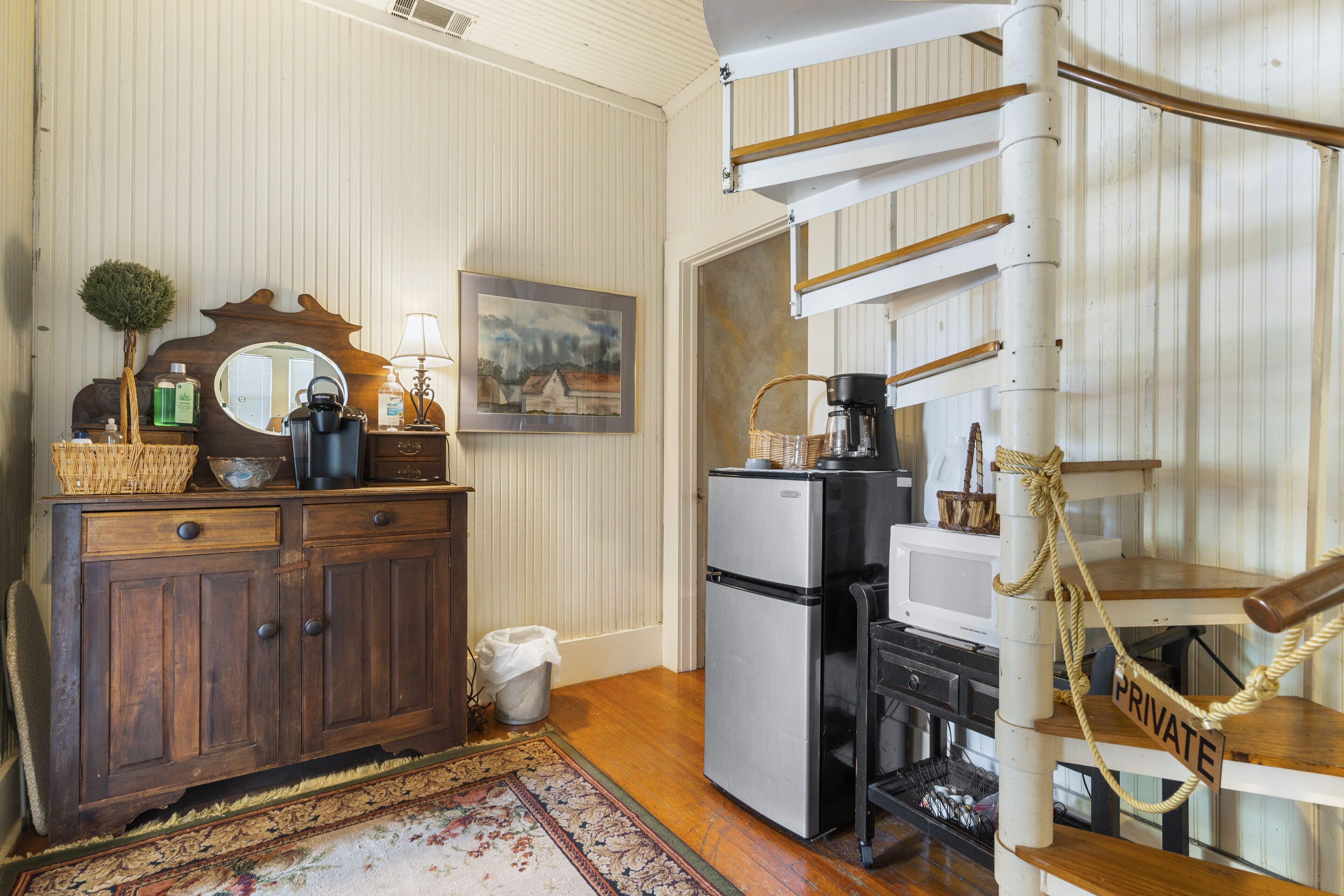 A compact kitchen with wooden cabinets, a refrigerator, and a coffee maker.