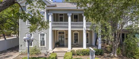 A two-story house with a front porch, columns, and a sign indicating a restaurant.