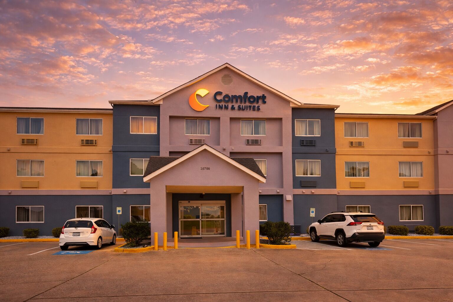 A Comfort Inn & Suites hotel with a modern facade, multiple floors, and a parking lot with two cars.