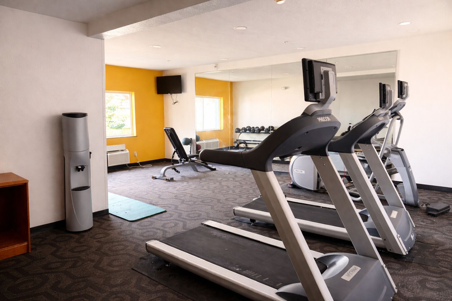 Une salle de sport équipée de tapis de course, d’un vélo d’appartement et d’un banc de musculation.