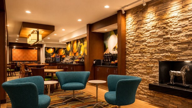 A modern hotel lobby with a stone wall, a bar area, and seating with teal chairs. - Comfort Inn & Suites Texas City I-45 (Texas City)