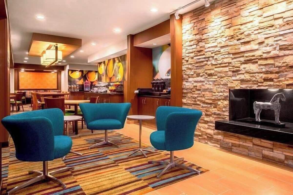 Un vestíbulo con pared de piedra, chimenea y sillones azules.