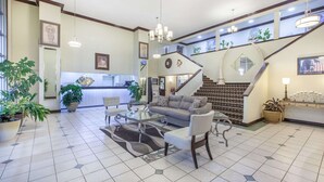 A spacious living area with a sofa, armchairs, a coffee table, and a staircase leading to an upper level. - Super 8 by Wyndham Tyler TX (Tyler)