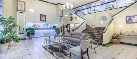 Uma sala de estar ampla com sofá, poltronas, uma mesa de centro e uma escada que leva a um andar superior.