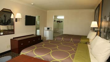 A hotel room with two beds, a desk, a dresser, a microwave, and a bathroom visible through an open door.