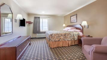 Habitación de hotel con cama, cómoda, silla, espejo grande y ventana con cortinas.