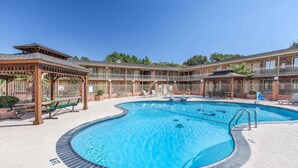 A pool area with a circular pool, lounge chairs, and a covered seating area. - Super 8 by Wyndham Tyler TX (Tyler)
