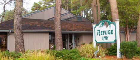A building with a sign reading "Refuge Inn" surrounded by trees and vegetation.
