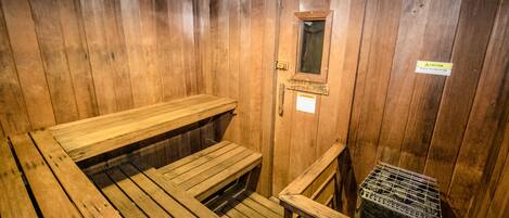 Un sauna en bois, doté de bancs et d’une petite fenêtre.