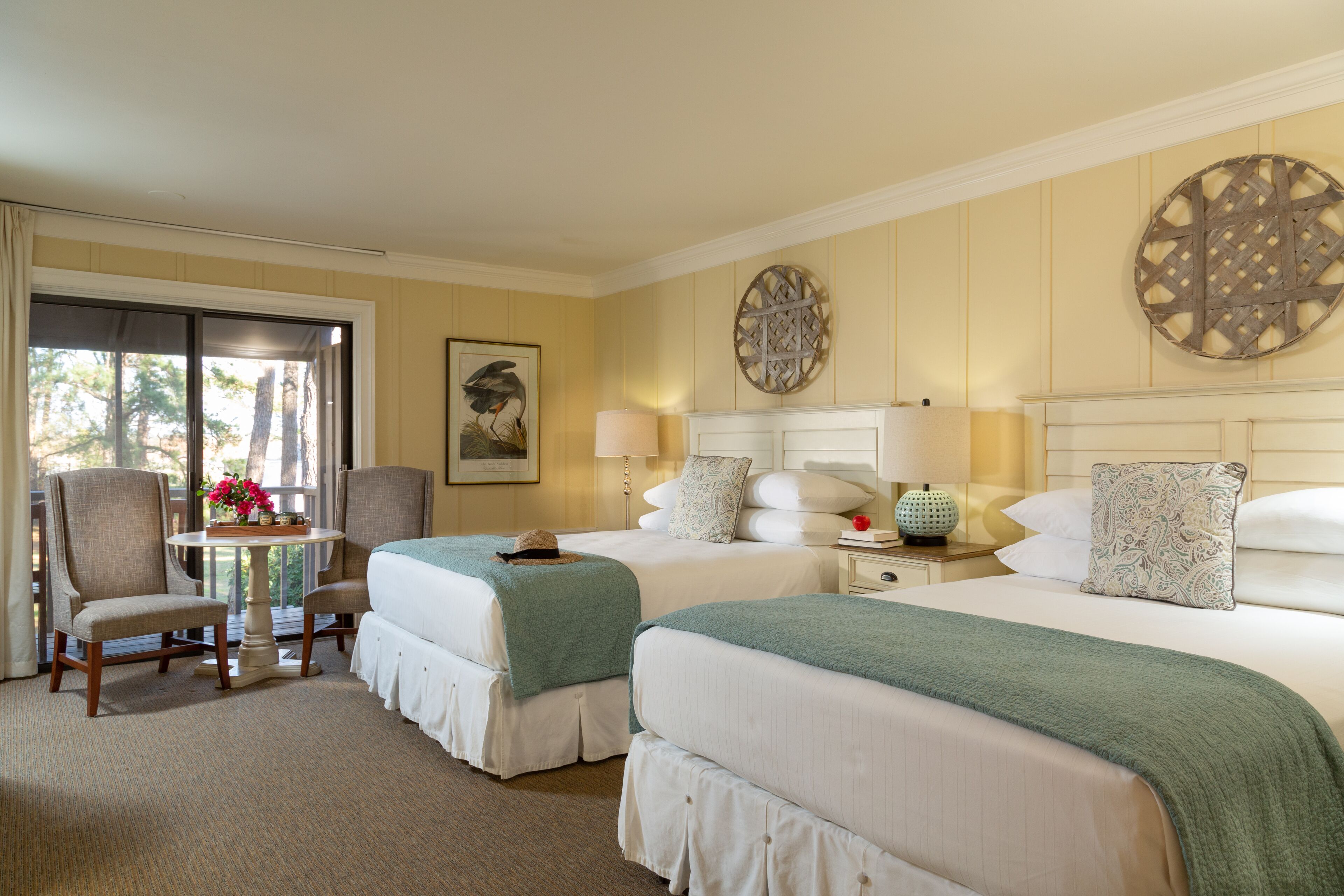 Une chambre d’hôtel avec deux lits, une table décorée de fleurs et une chaise.