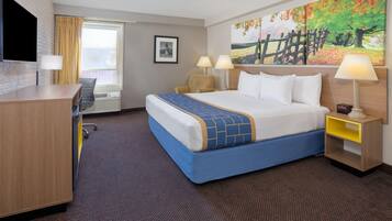 A hotel room with a large bed, a desk, a chair, a TV, and a painting on the wall.