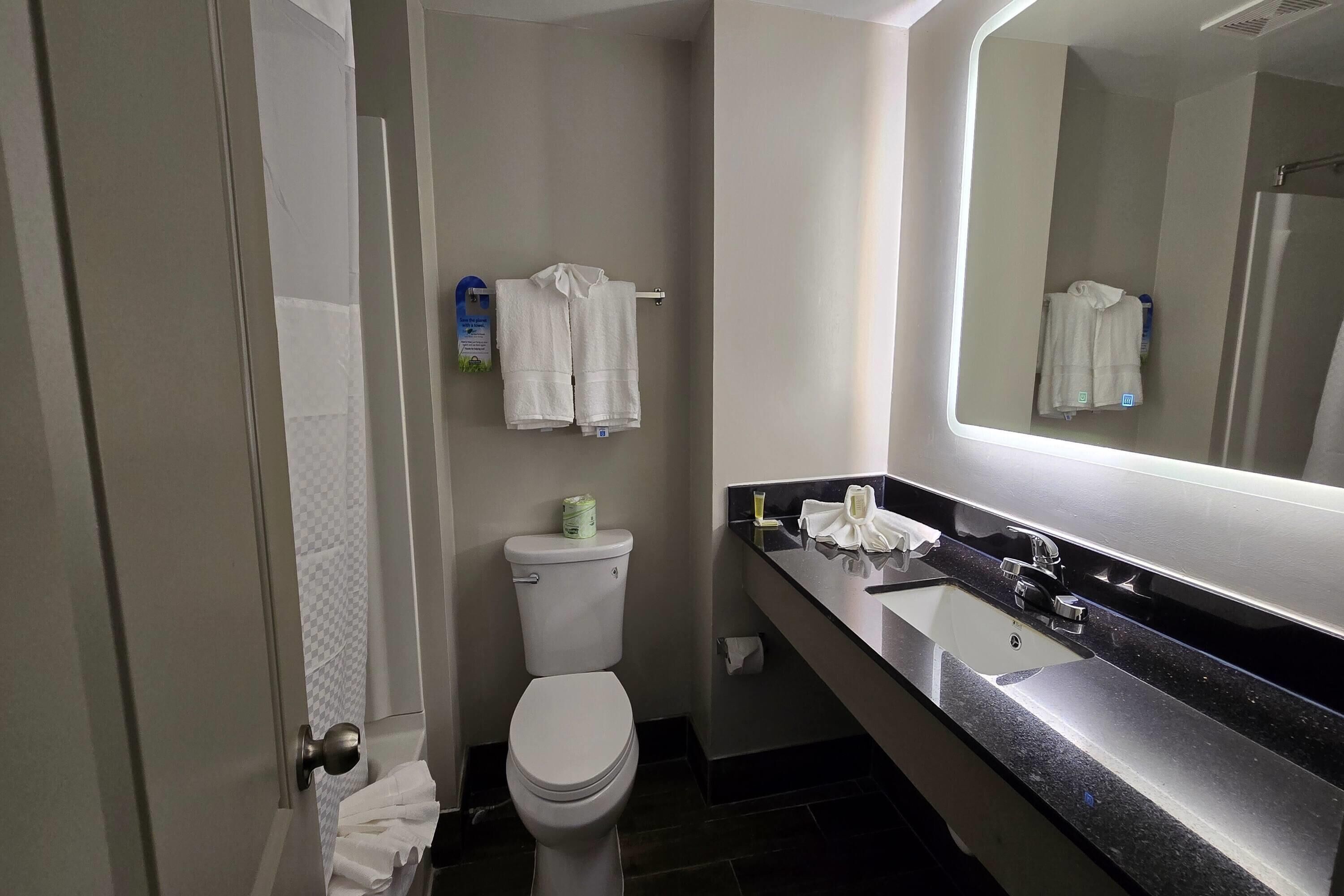 Un baño moderno con inodoro, lavabo y espejo.