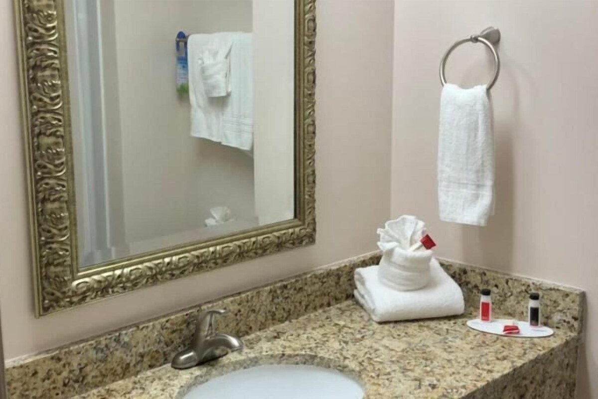 A bathroom with a sink, mirror, towel rack, and toiletries.