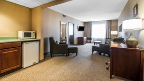 A hotel room with a kitchenette, a flat-screen TV, a desk with a lamp, and a seating area with a sofa and armchairs. - Quality Inn & Suites Towanda (Towanda)
