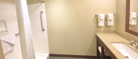 Un baño con ducha, lavabo y espejo.