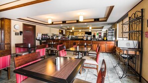 A restaurant with wooden tables and chairs, a kitchen area, and a fire safety sign. - Quality Inn & Suites Towanda (Towanda)