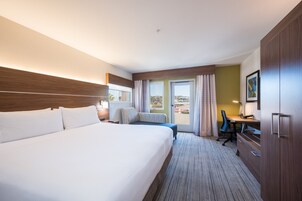 Habitación de hotel con una cama grande, un escritorio, una silla y vistas al exterior.