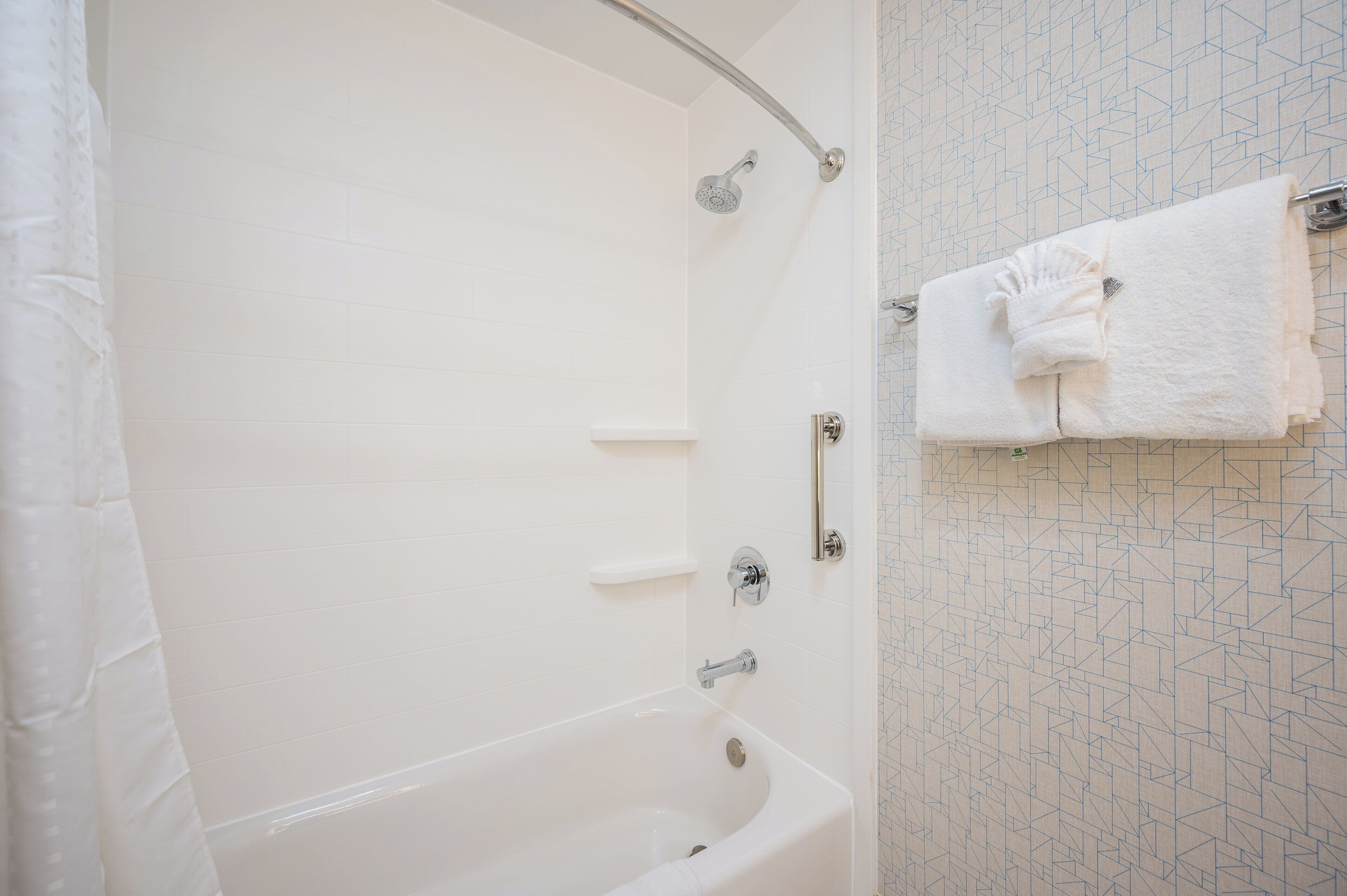 A bathroom with a bathtub, a shower, and a towel rack with a towel.