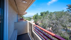 Un balcón con barandal rojo que ofrece vistas panorámicas de árboles y un paisaje lejano.