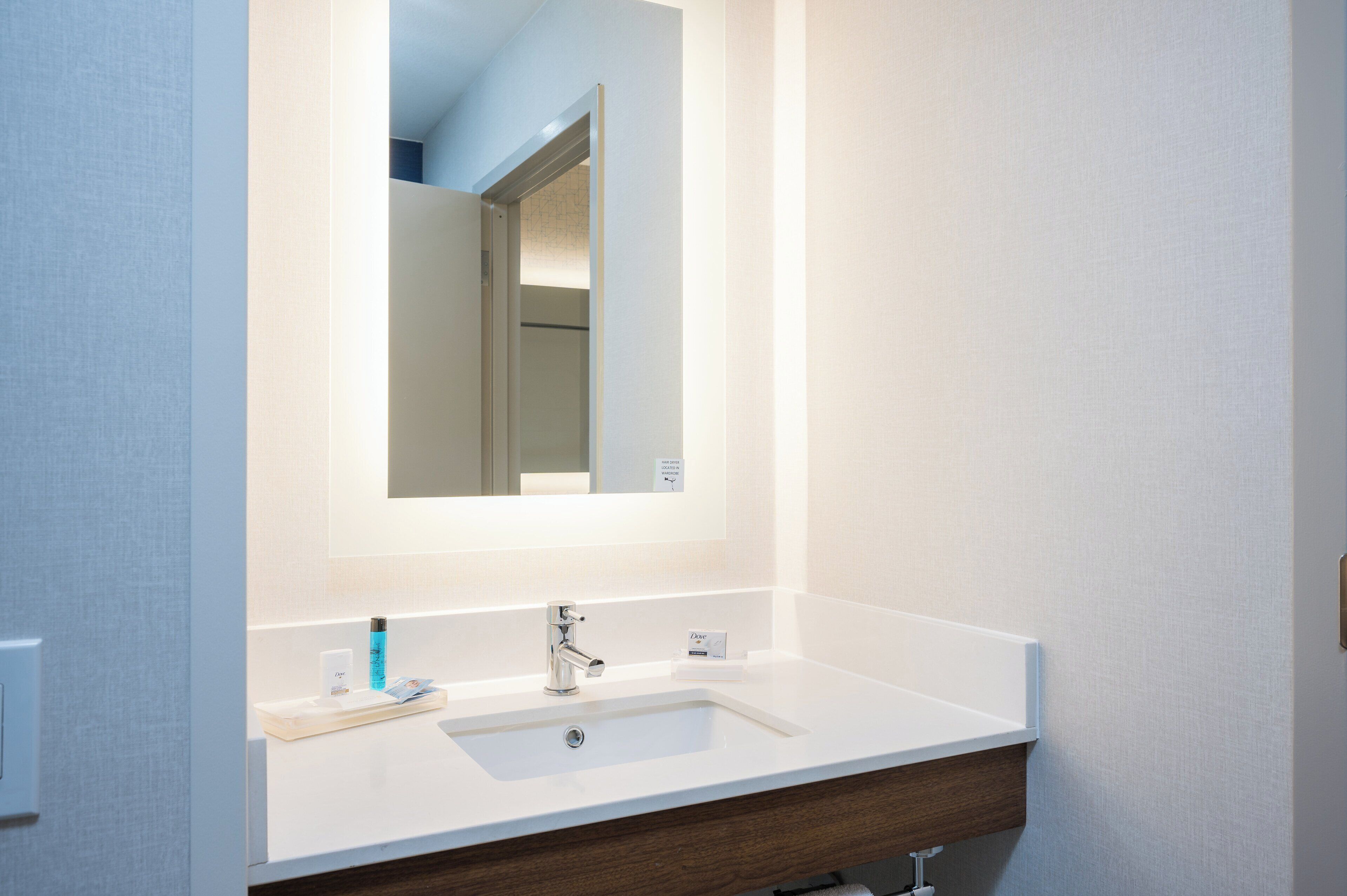 A bathroom with a white sink, a mirror, and a towel rack.