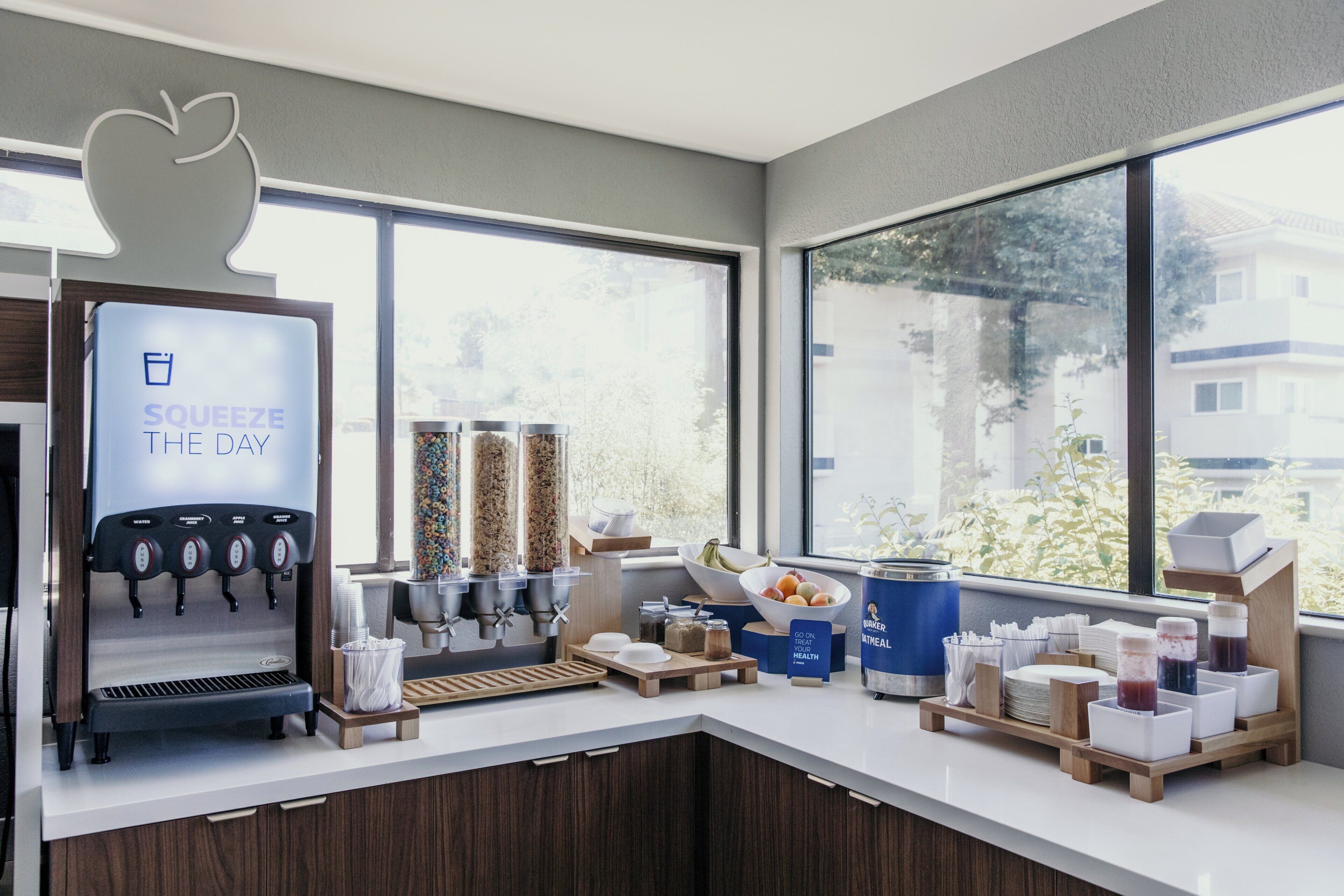 En modern kaffestation med en dryckesdispenser med företagets logotyp, ett varierat utbud av drycker och utsikt över omgivningen.