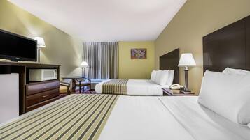 A hotel room with a bed, a TV, a desk, a chair, a lamp, and a window with curtains.