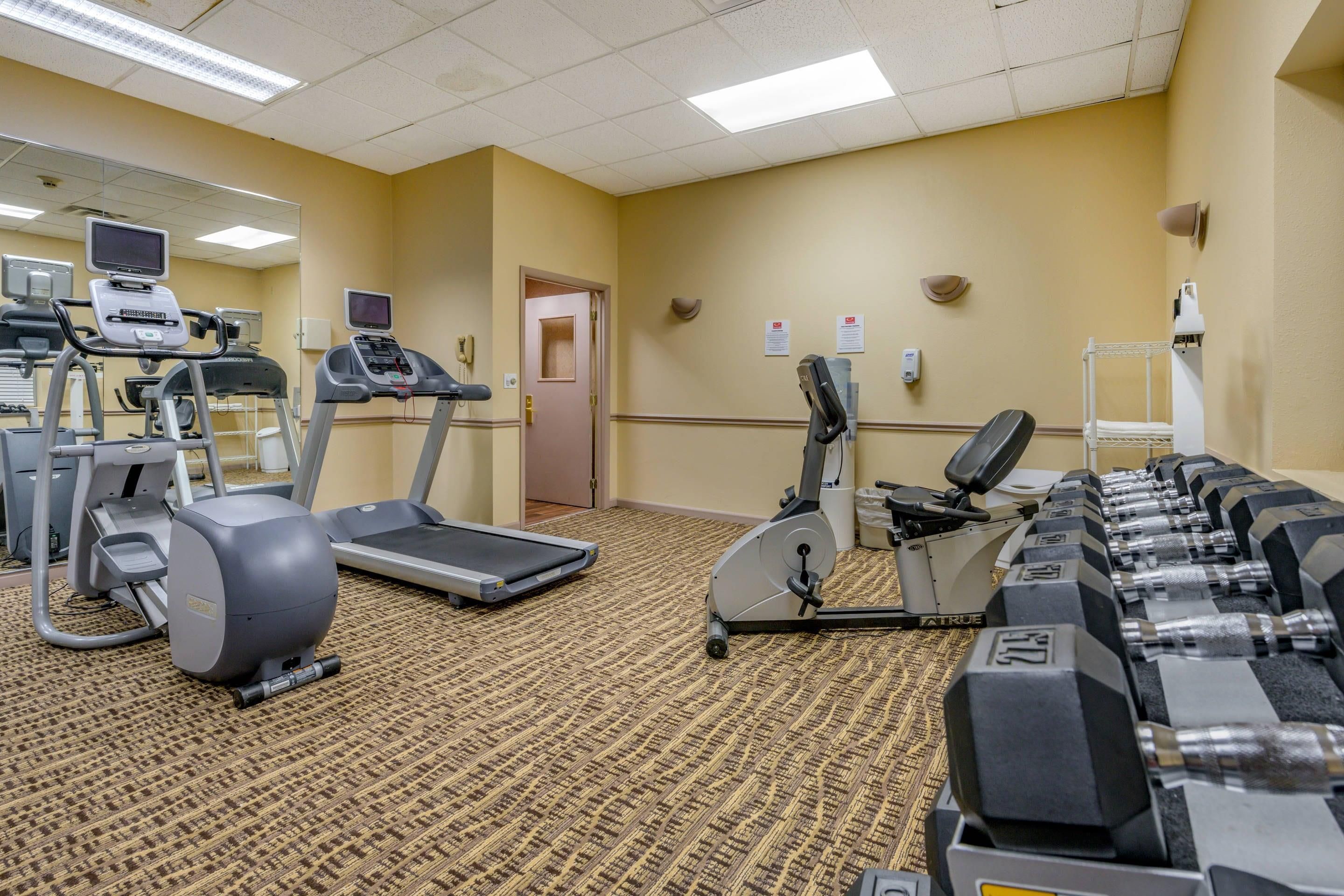 A hotel gym with treadmills, elliptical machines, and free weights.