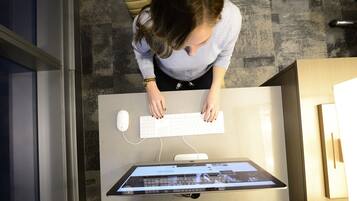 Una persona seduta a una scrivania con una tastiera e un monitor che mostra un sito web.