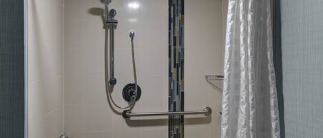 A shower with a handheld showerhead, a wall-mounted faucet, and a towel rack.