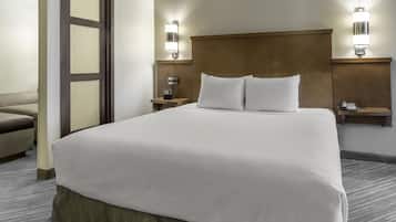 A hotel room with a large bed, two bedside tables, a chair, and a wall-mounted phone.