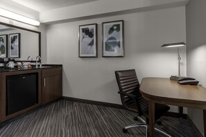 Une chambre d’hôtel équipée d’un bureau, d’une chaise et d’une petite kitchenette.