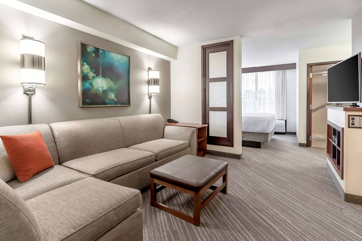 Een hotelkamer met een bank, een kleine tafel, een bed, een televisie en een schilderij aan de muur.
