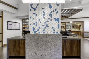 Un mostrador de recepción con encimera de mármol, un pared con diseño geométrico y un mapa en la pared.