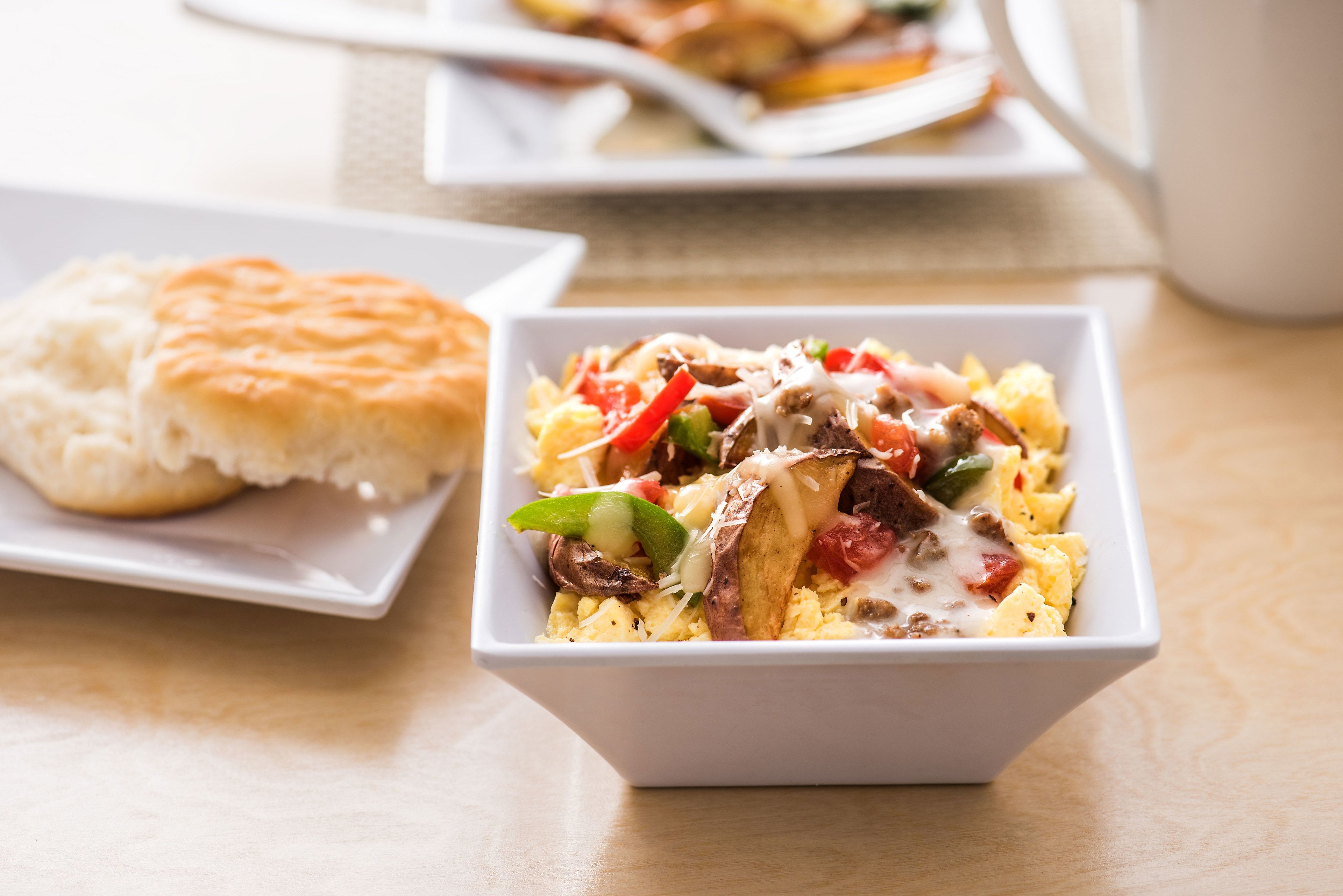 A breakfast dish with eggs, vegetables, and cheese on a white plate.