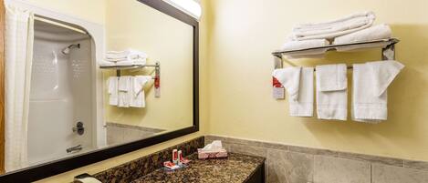 A bathroom with a sink, mirror, towel rack, toilet, and shower.
