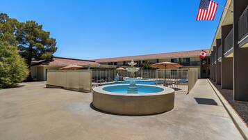 A courtyard with a central fountain, outdoor seating, and a pool area.