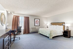 Ein Hotelzimmer mit Bett, Schreibtisch, Stuhl und einem großen Spiegel.