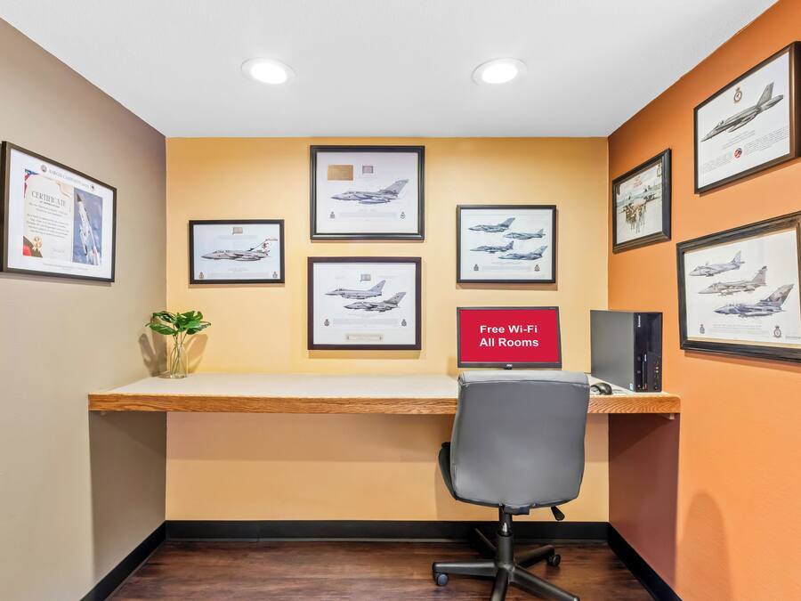 Una habitación con escritorio, fotografías de aviones enmarcadas, una planta y un letrero que indica Wi-Fi gratuito.