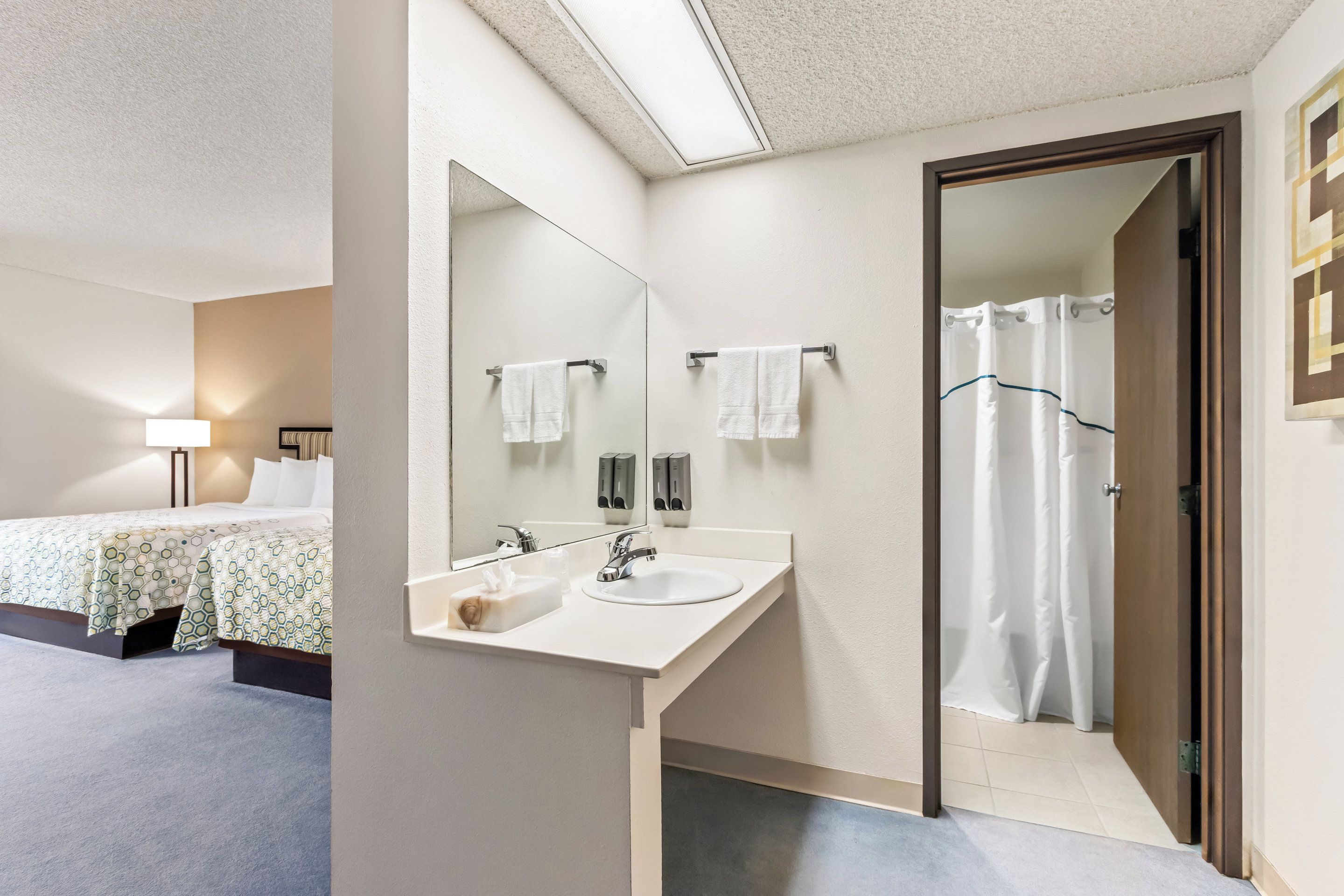 A hotel bathroom with a large mirror, a sink, and a shower.