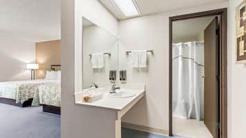 A hotel bathroom with a large mirror, a sink, and a shower.