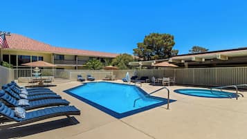 A pool area with lounge chairs and a smaller pool.