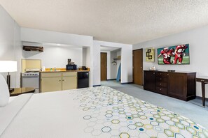 Une chambre d’hôtel comprenant un lit, une kitchenette, une télévision et un couloir menant à une autre pièce.