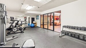 Ett gym med träningsutrustning, en viktbänk och ett väggmonterat ställ för hantlar.