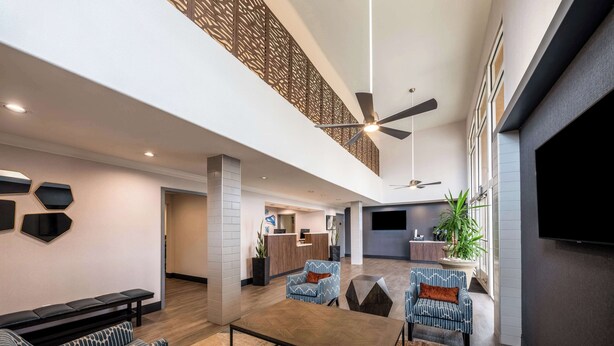 Un'ampia hall con soffitto alto, zone relax, una reception e un grande schermo televisivo.