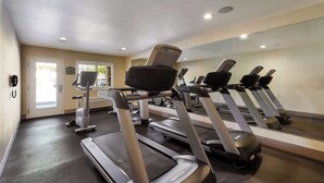 Una palestra con tapis roulant, una cyclette ed uno specchio che riflette le attrezzature.