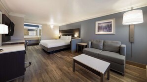 Una camera d'albergo con un letto, un divano, una scrivania e una lampada.